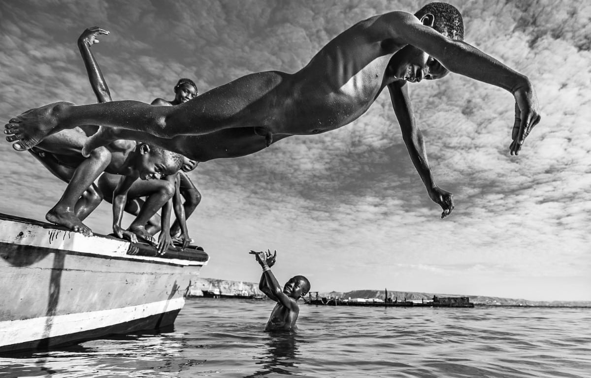 Boys jumping off of a boat into the water