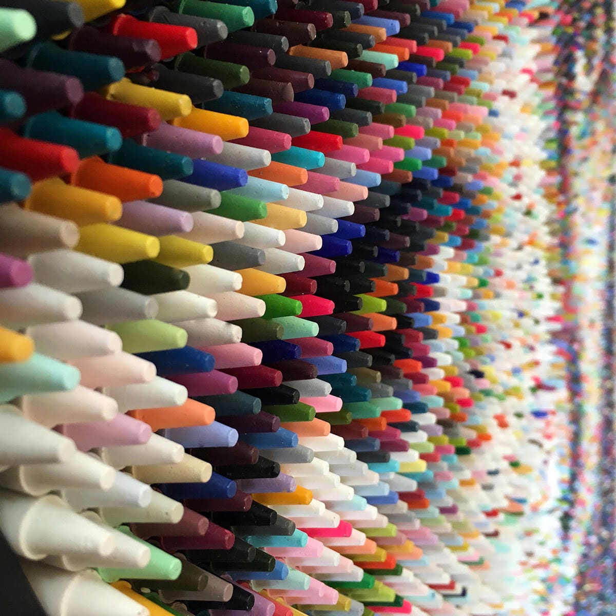 An example of Art Materialism - a close up of countless stacked crayons that look like a portrait of a face from a distance by artist Christian Faur
