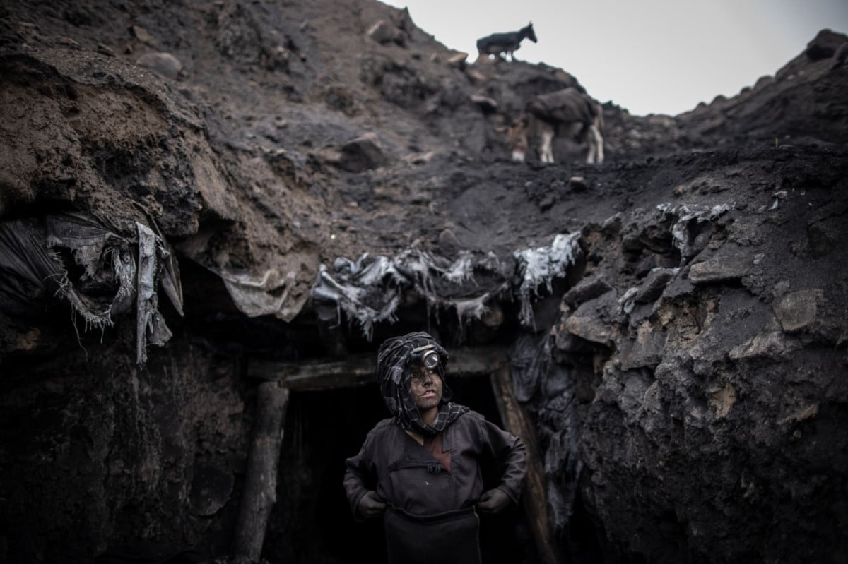 A young boy working in an informal coal mine in Chinarak stands outside the entrance.