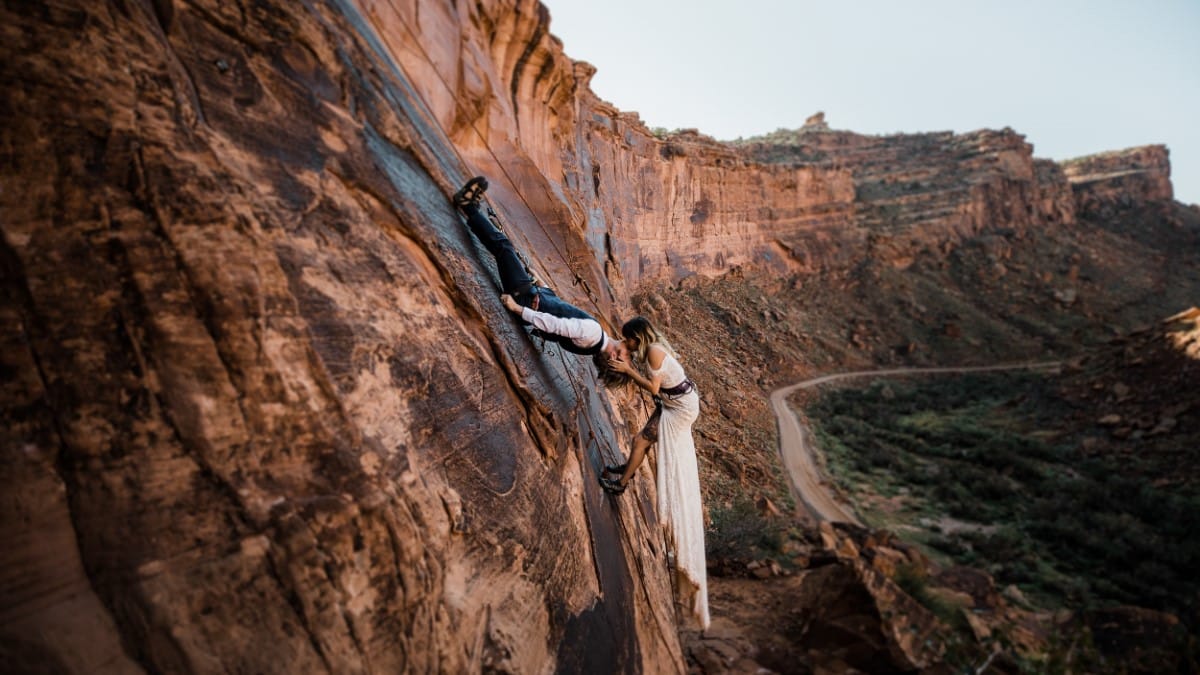 Bride and groom scaling a cliff