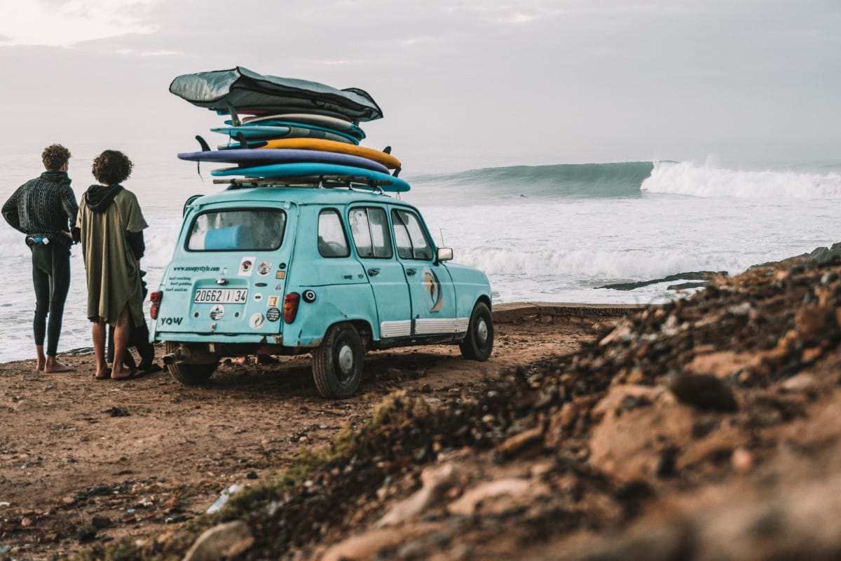 Car parked by the ocean with surfboards on the top