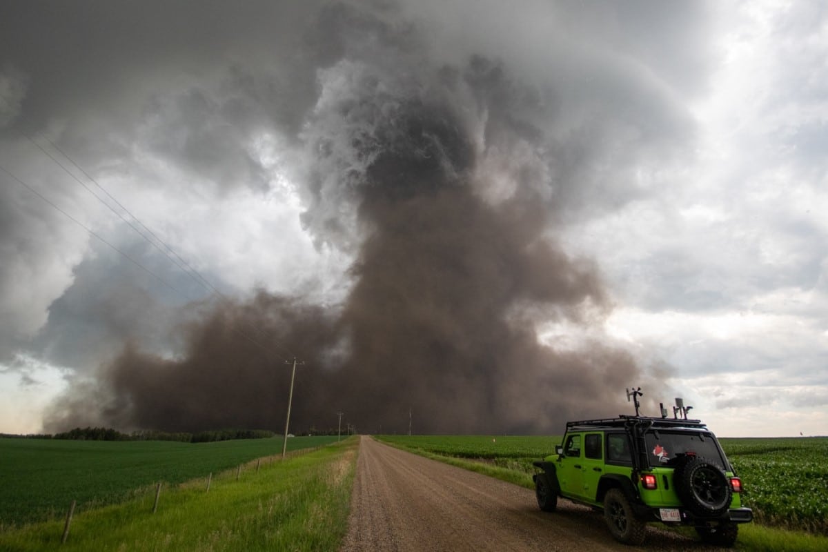 Alberta's strongest tornado since the infamous 1987 Black Friday twister etches its mark on the landscape southeast of Didsbury, Alta. on July 1, 2023, while a chase vehicle looks on.