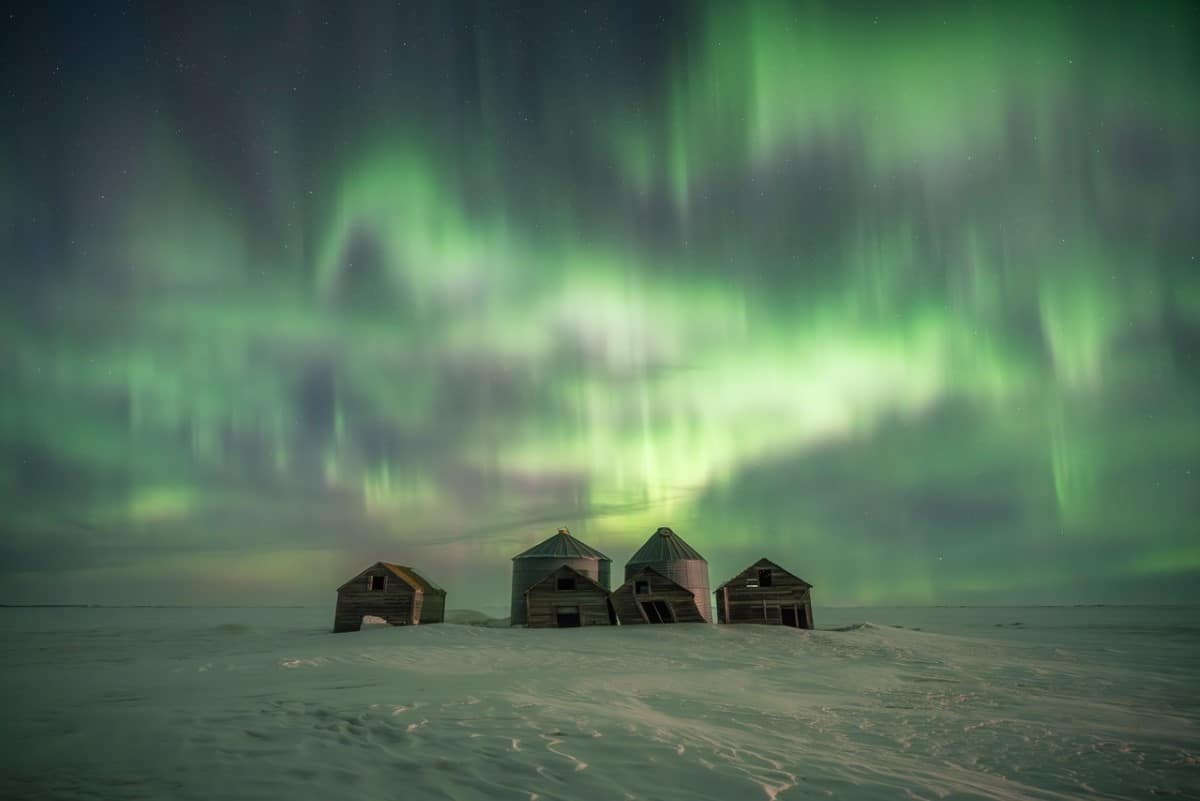 A G3 geomagnetic storm produces a dazzling display of aurora borealis over dilapidated farm structures in Pense, Sask.