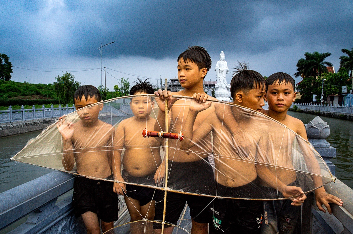 Five boys are holding their kite before a heavy rain in Hanoi, Vietnam