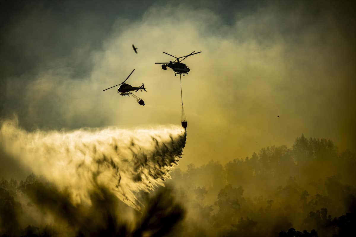 Helicopters releasing water over a fire