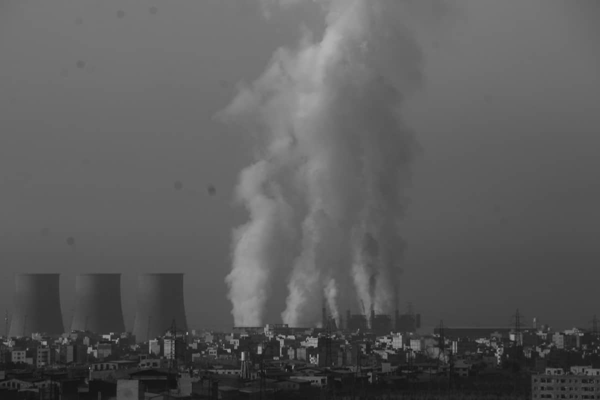 Black and white photo of industrial factory emitting smoke