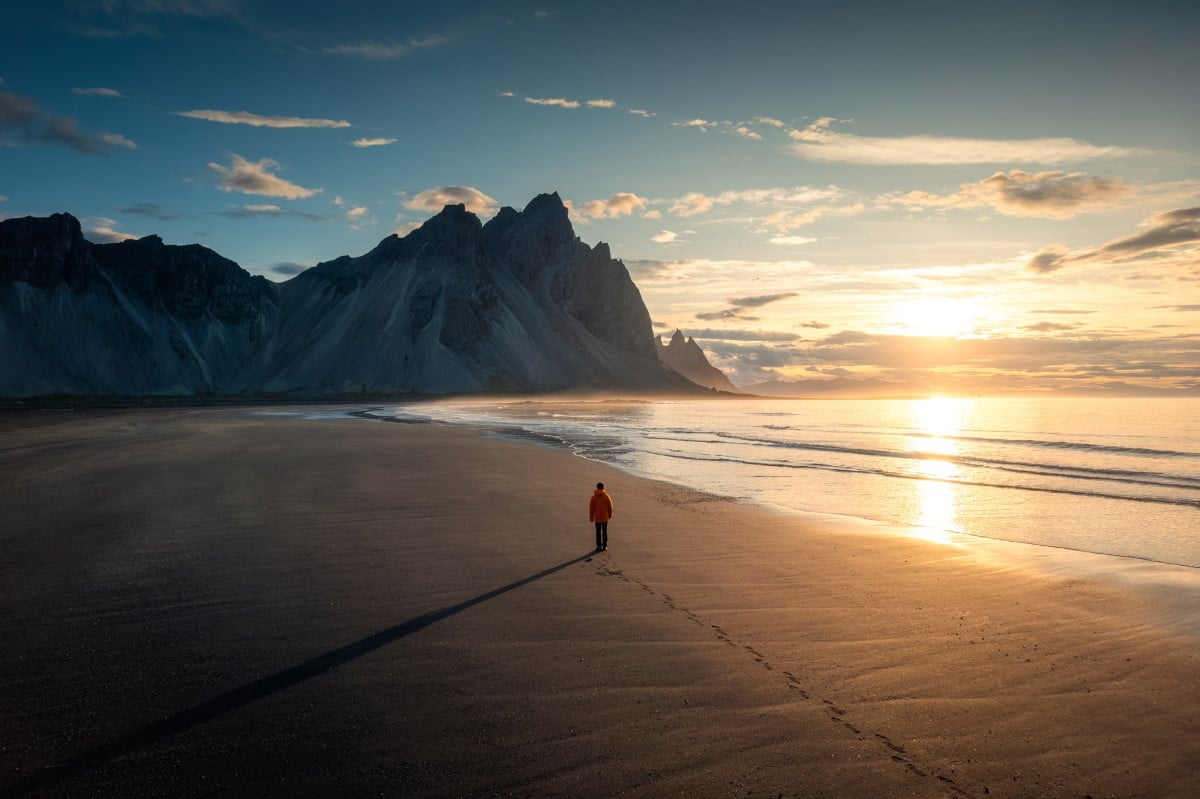 A man walking along the beach towards Vestrahorn mountain in Iceland.