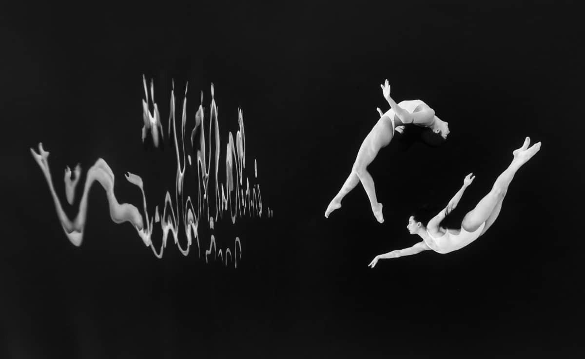 Creative black and white photo of dancers underwater
