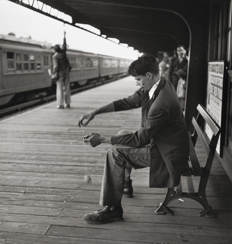 Man sitting on a bench with a yoyo waiting for the subway in New York in 1949