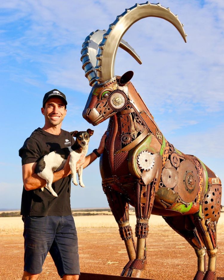 Jordan Sprigg Poses With His Dog In Front Of His Metal Ibex Sculpture