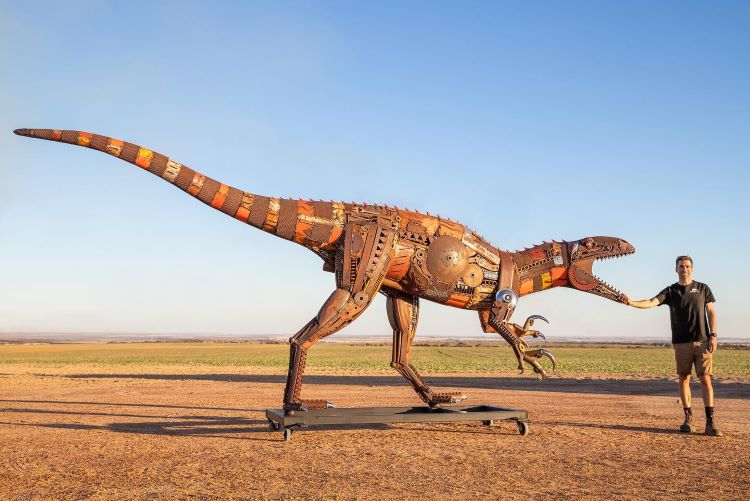Jordan Sprigg Stands With His Metal Dinosaur Sculpture