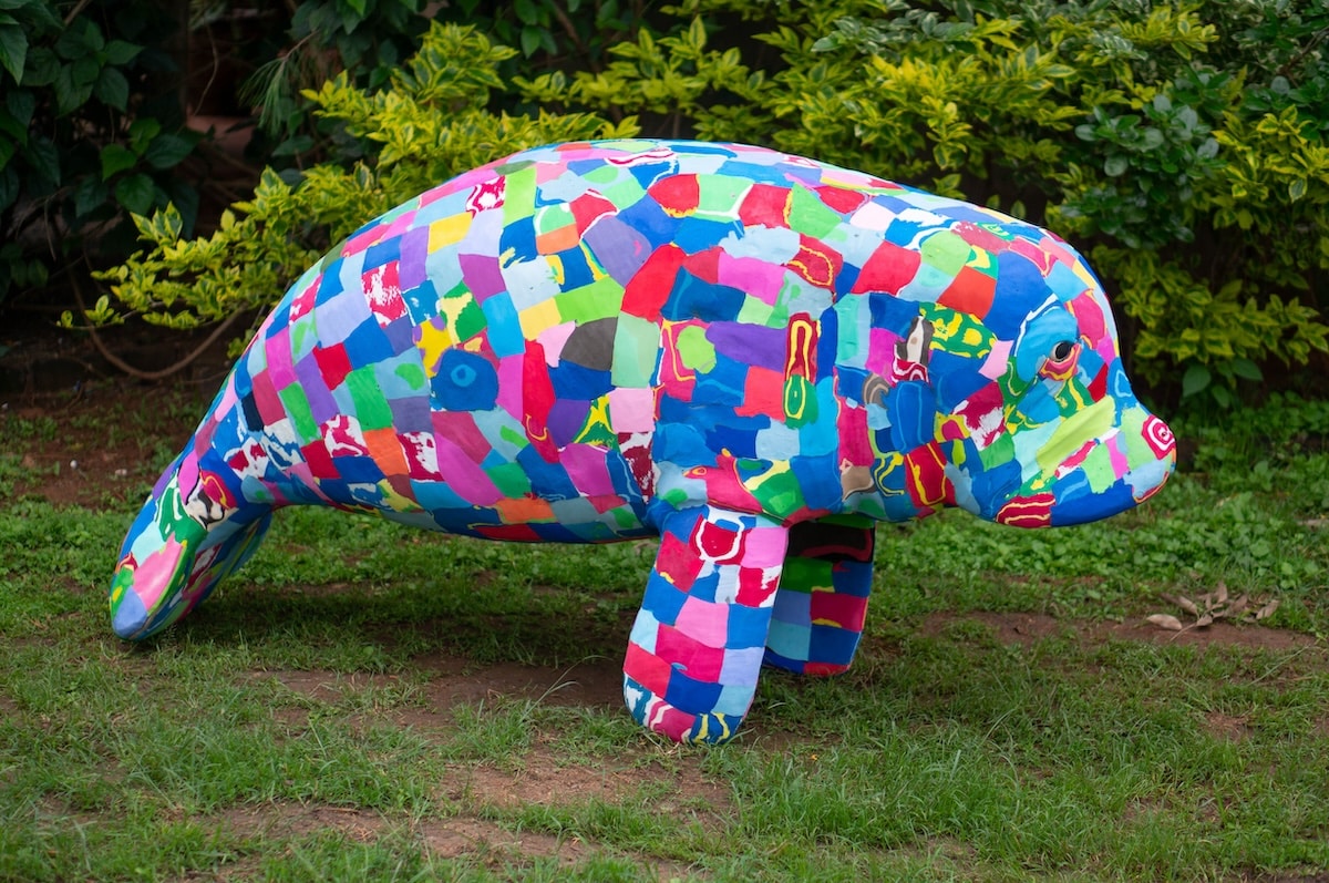 Life-size manatee sculpture made of colorful flip-flops