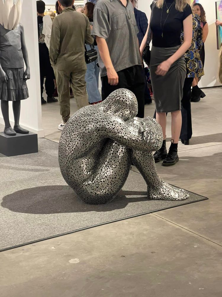 A Sculpture Of A Person In The Fetal Position Made Of Bicycle Chains