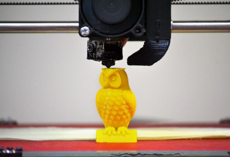 Modern 3D printer printing figure close-up. Automatic three dimensional 3d printer performs plastic yellow colors modeling in laboratory. Progressive modern additive technology