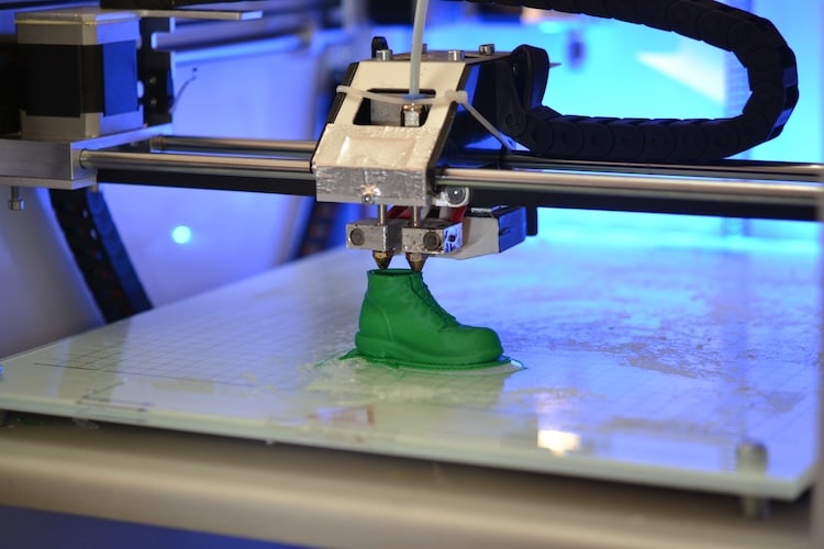 3D printer prints the form of molten plastic green close-up. Automatic three dimensional 3d printer performs plastic modeling in laboratory. Progressive modern additive technology
