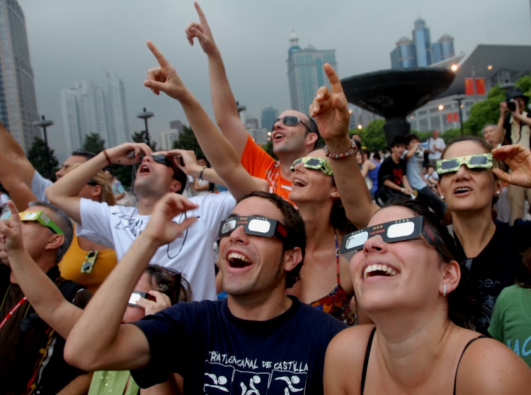 Foreign visitors look through special glasses at the partial eclipse of a total solar eclipse at the Peoples Square in Shanghai, China, Wednesday, July 22, 2009. The longest total solar eclipse of the 21st century passed through Asia from India to China on Wednesday as millions of people gathered to watch the phenomenon.
