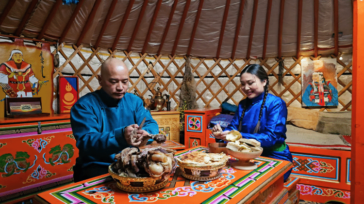 Mongolian Man And Woman Eating Food Around Table