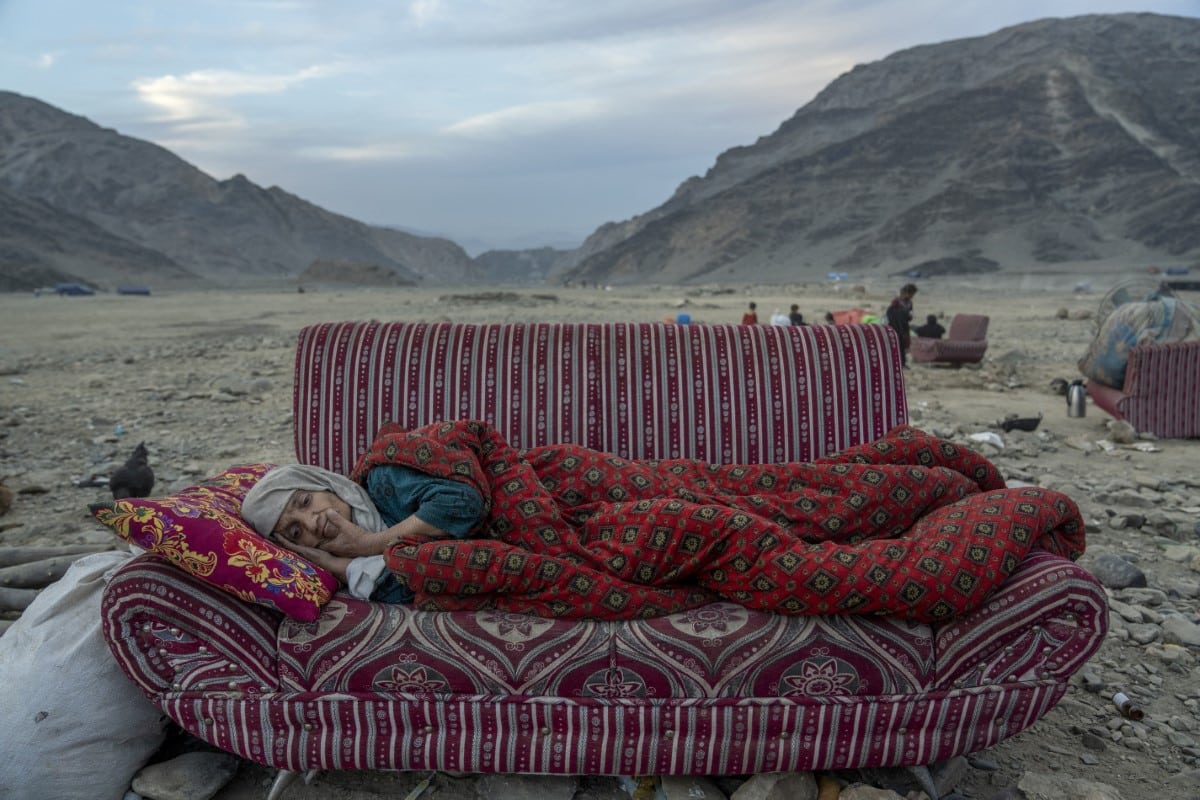 An Afghan woman rests in the desert, near a camp housing people recently deported from Pakistan, close to the Pakistan-Afghanistan border. 
