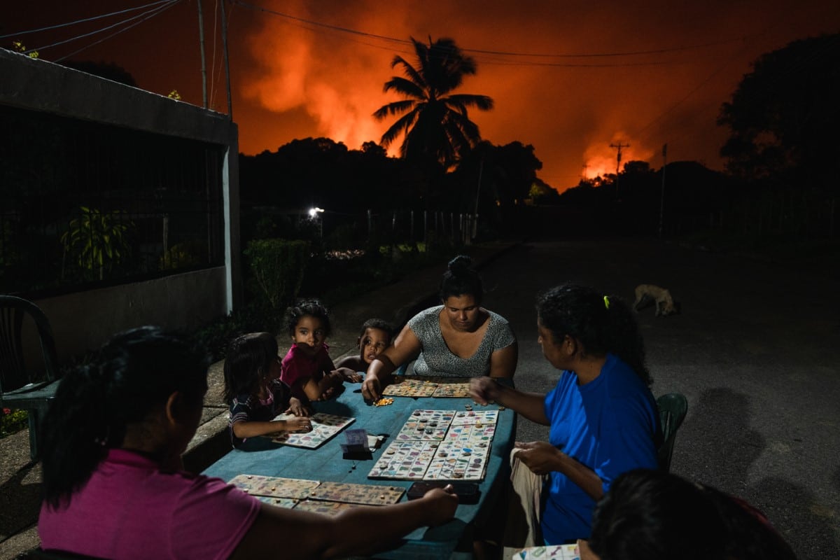 Neighbors play Animal Lotto under a sky lit by one of the world’s largest gas flares. 