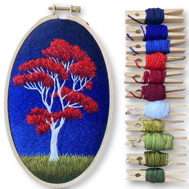 Embroidered Red Tree On Hill With Clothespins Holding Embroidery Thread Beside It