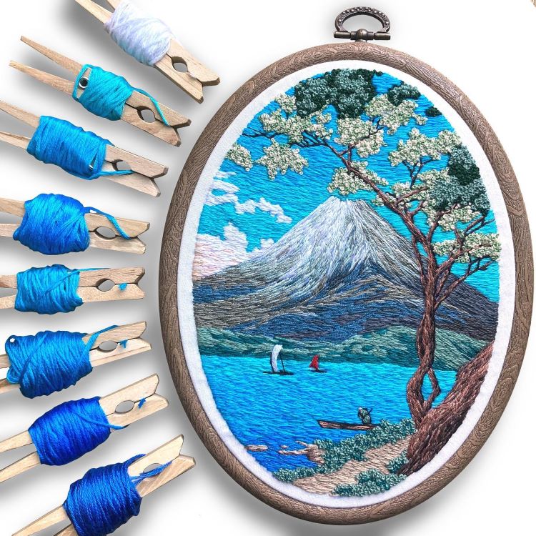 Embroidered Mountain Scene With Clothespins Holding Embroidery Thread Beside It