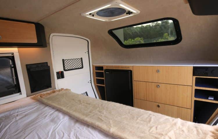 Photo Showing The Inside Cabin Of A Camper, Featuring The Bed And Shelving