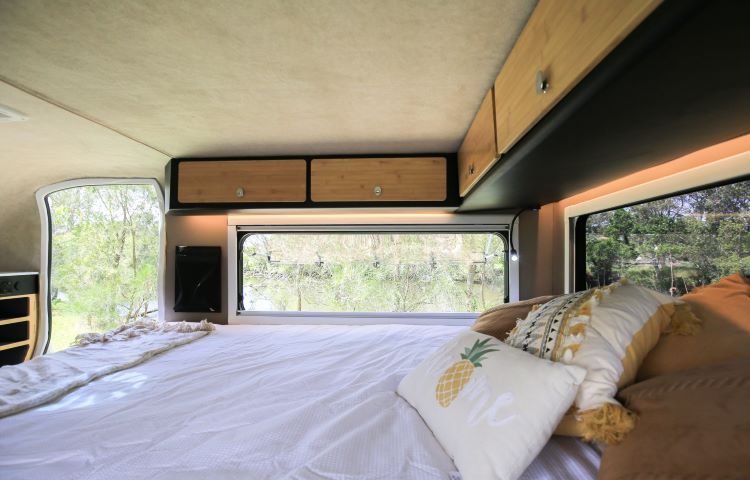 Photo Showing The Inside Cabin Of A Camper, Featuring The Bed And Shelving Above It
