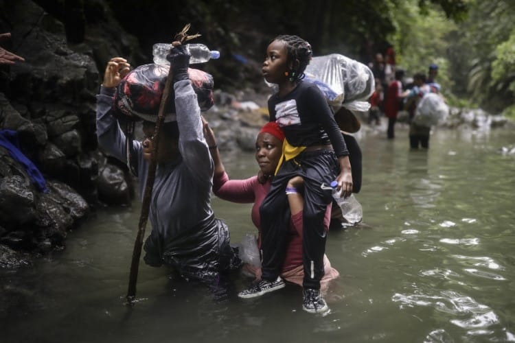 Haitian migrants wade through water as they cross the Darién Gap from Colombia to Panama 