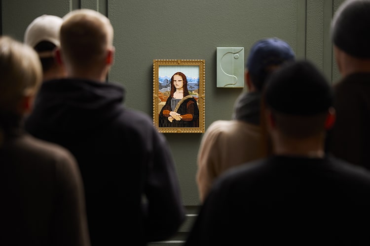 LEGO Mona Lisa on display on a gallery wall with a crowd of people viewing it similar to the real Mona Lisa in the Louvre