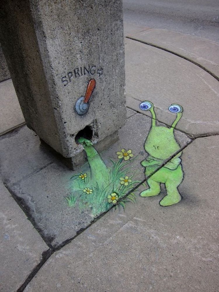 Chalk Art Of Green Alien Creature Standing In Front Of A Level Labelled "Spring" That Has Flowers And Grass Spilling Out Of It 