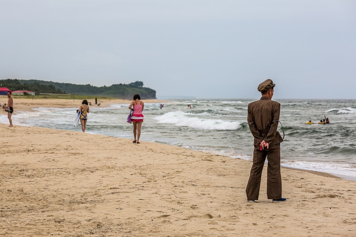 People walking on the beach in North Korea by Tariq Zaidi