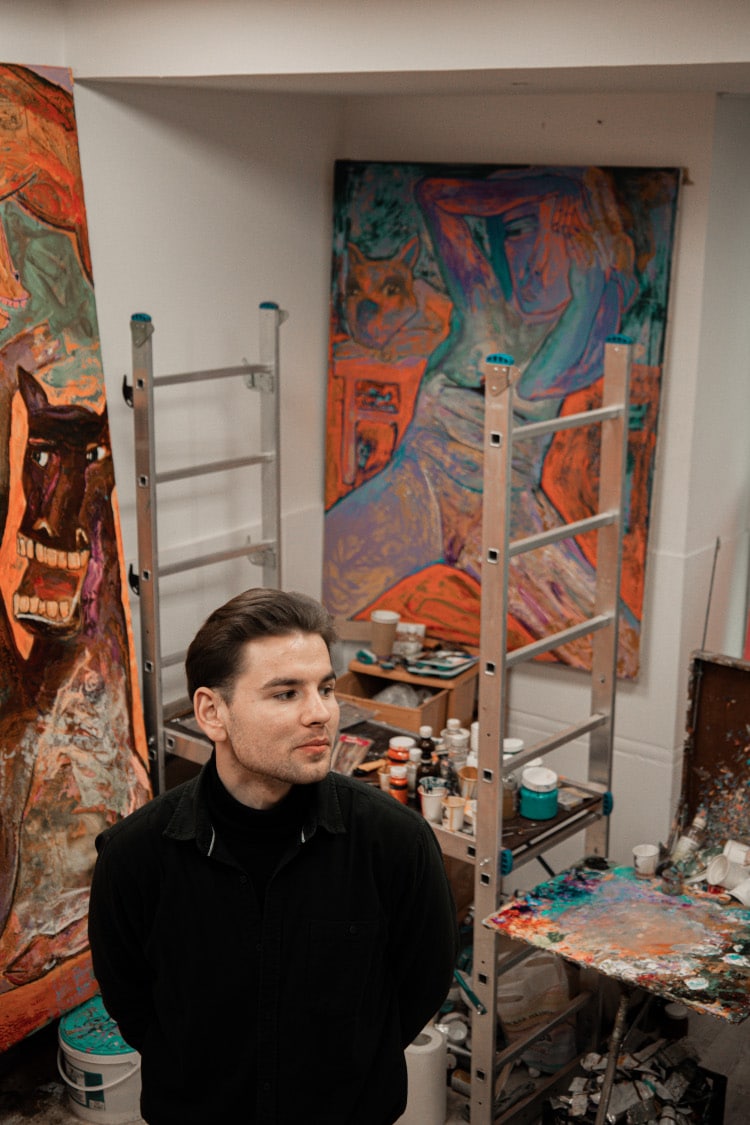 Artist Sergiu Ciochina poses with his paintings