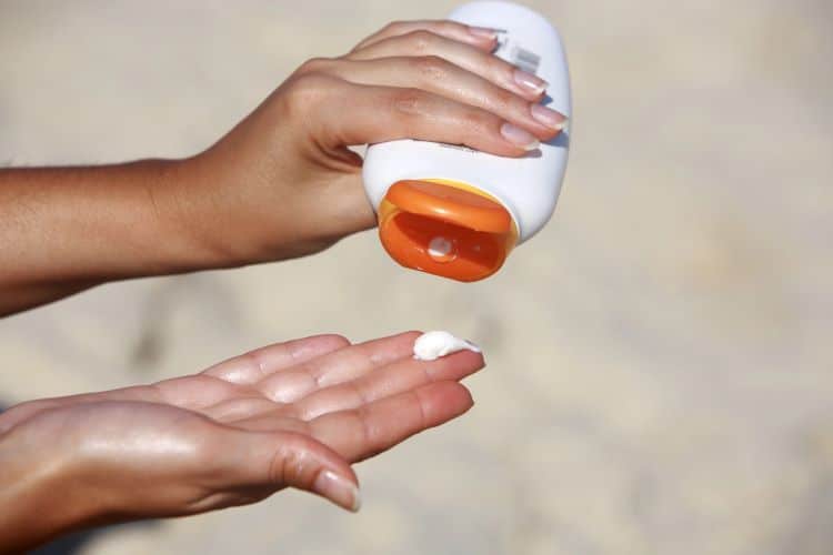 Photo Of Woman's Hand Squeezing Sunscreen Onto Her Other Hand