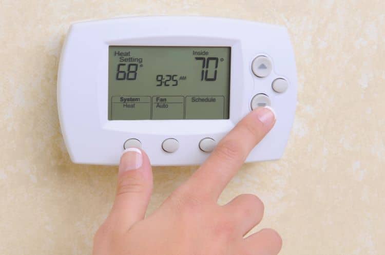 Hand Adjusting Thermostat On Wall