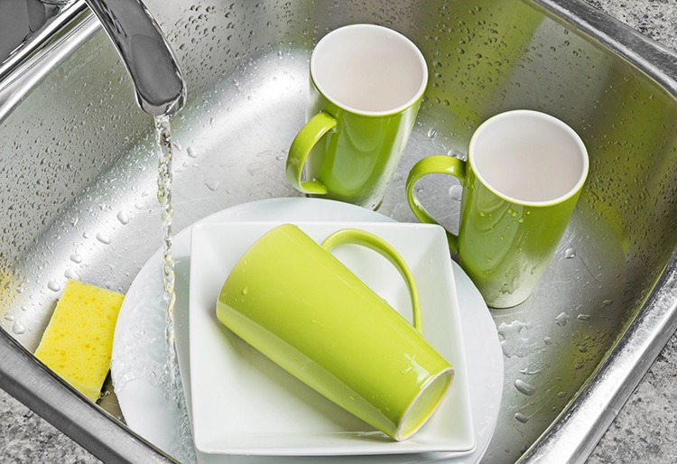 Empty coffee mugs in kitchen sink being washed