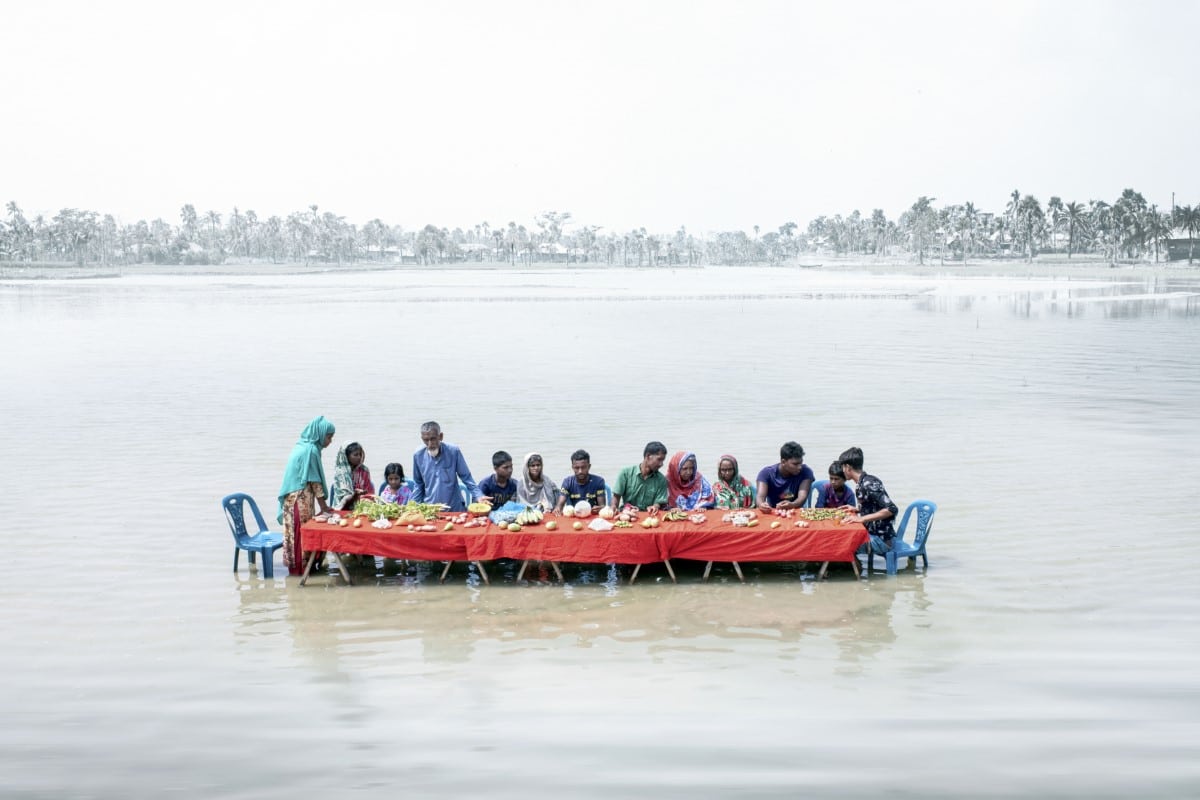 People in Bangladesh sitting at a long table in floodwaters