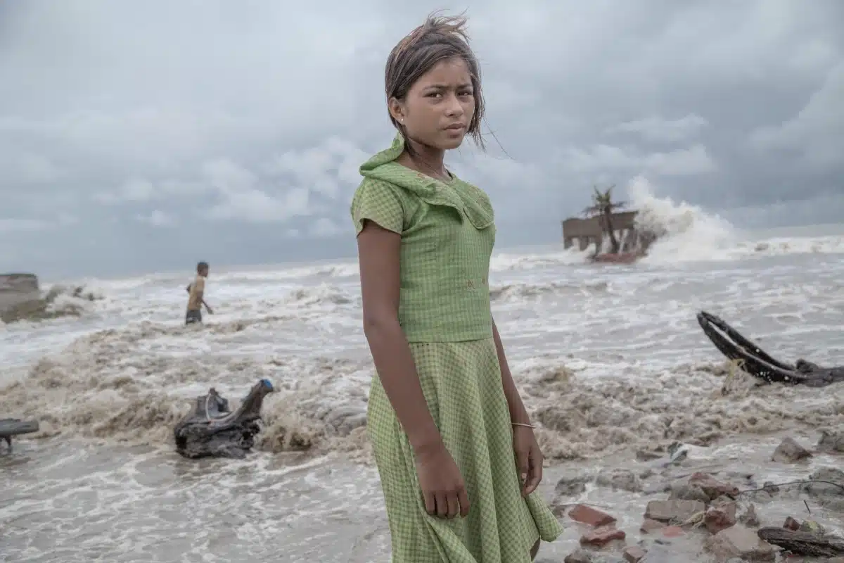 A girl standing in front of her ruined tea shop in Frazerganj, Sundarbans