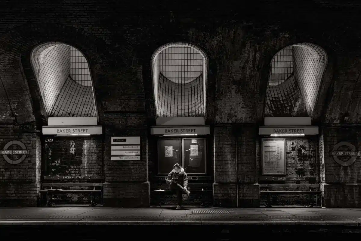 Black and white image of a woman sitting outside Baker Street tube station