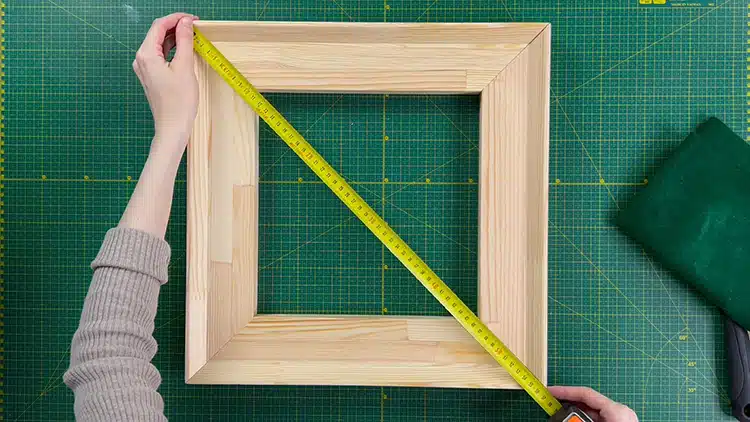 Luiza Niechoda measures out the size of her frame for her canvas.