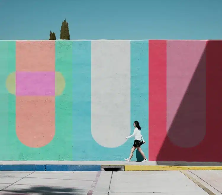 Woman walking in front of a colorful abstract mural