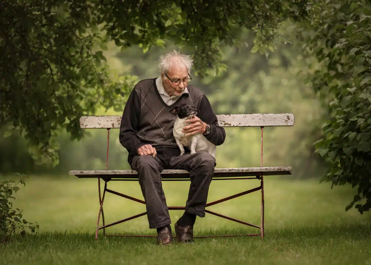 Elderly man sitting on a bench with his dog