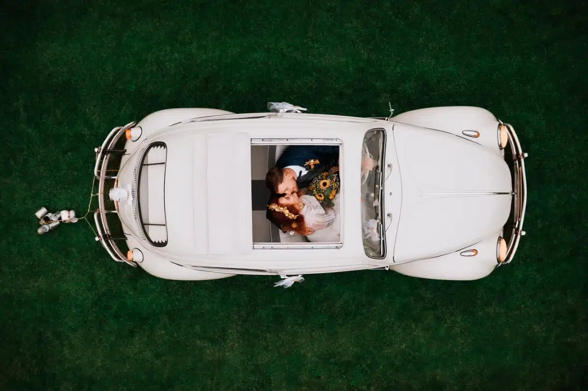 Aerial photo of newlyweds in a white Volkwagen Beetle