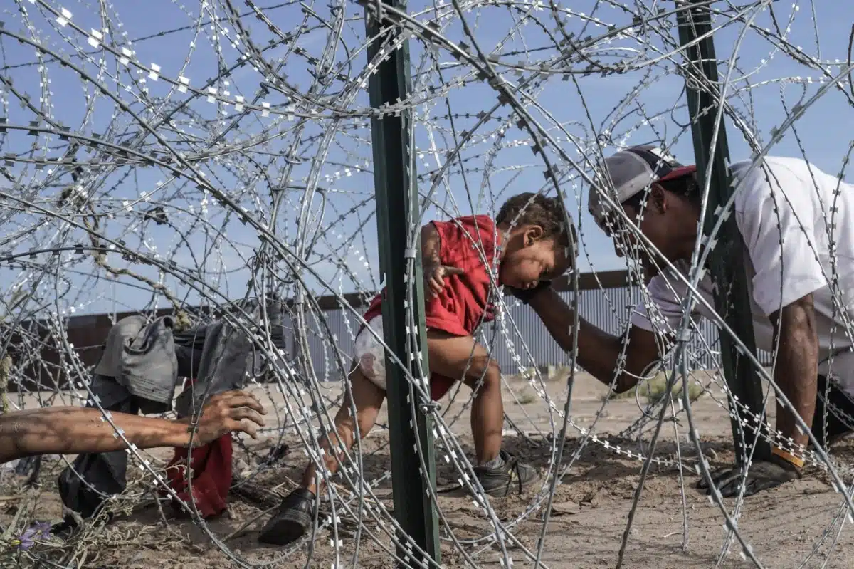 "A family, with a young child, makes their way through razor wire along the border wall separating the US and Mexico in Ciudad Juarez, Mexico