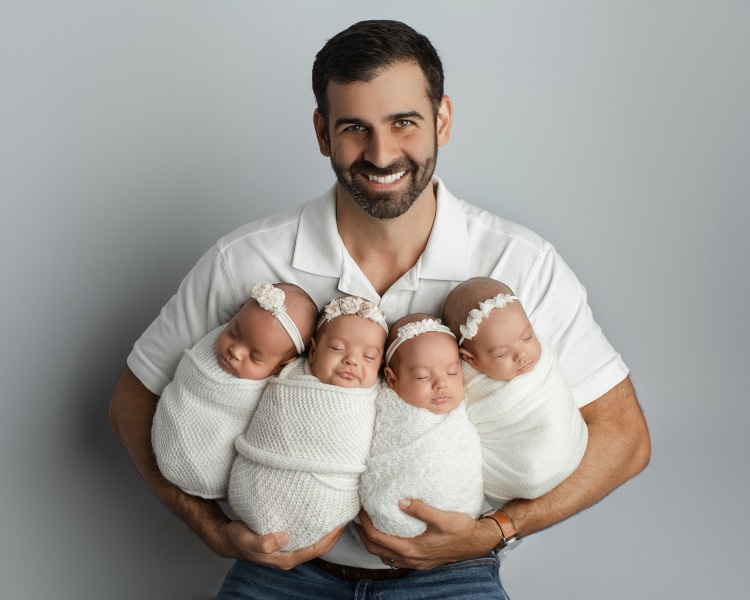 Baby quadruplets bundled up with their dad