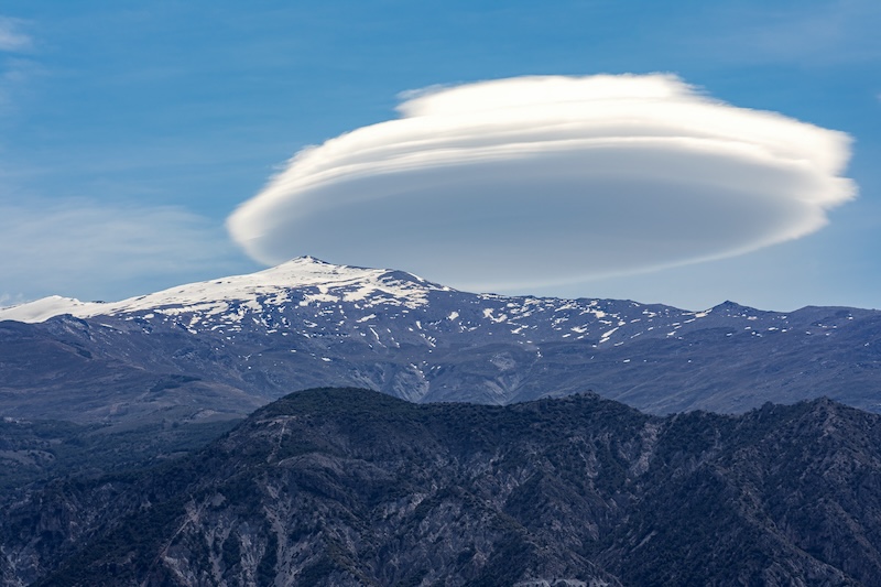 Lenticular cloud over a snowy mountain called Pico del Caballo in Sierra Nevada