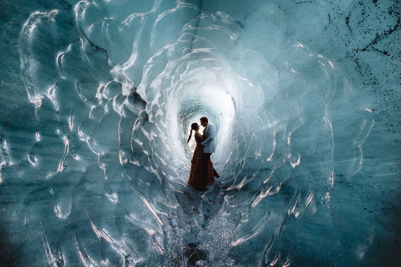 Couple during their elopement inside a small, blue ice tunnel on Katla Glacier.