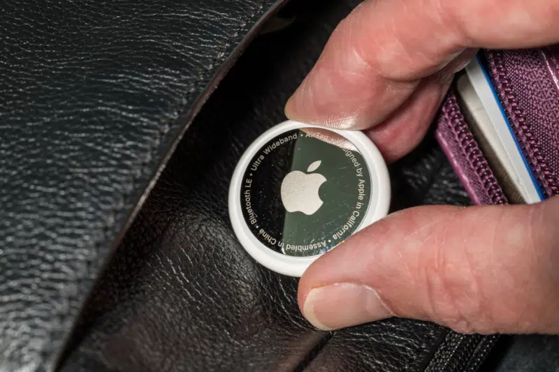 Apple AirTag device inserted into a leather purse