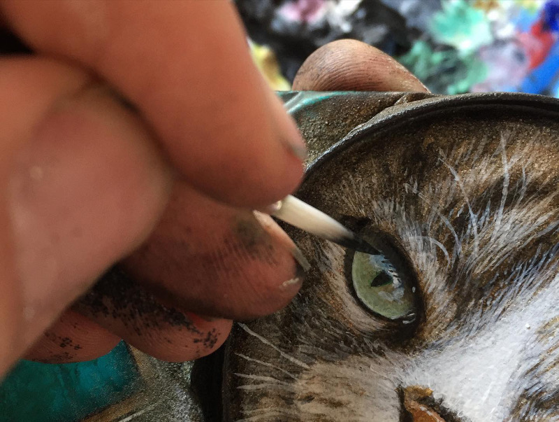 Artist My Dog Sighs painting a cat's eye on a can