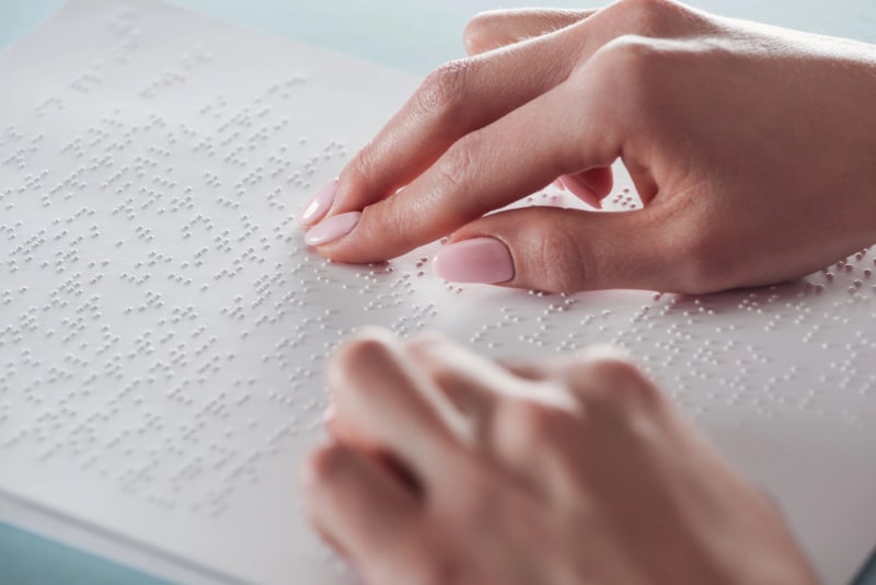 Women's hands on a page with braille text