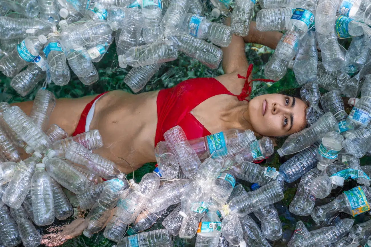 Woman in a bikini surrounded by plastic bottles